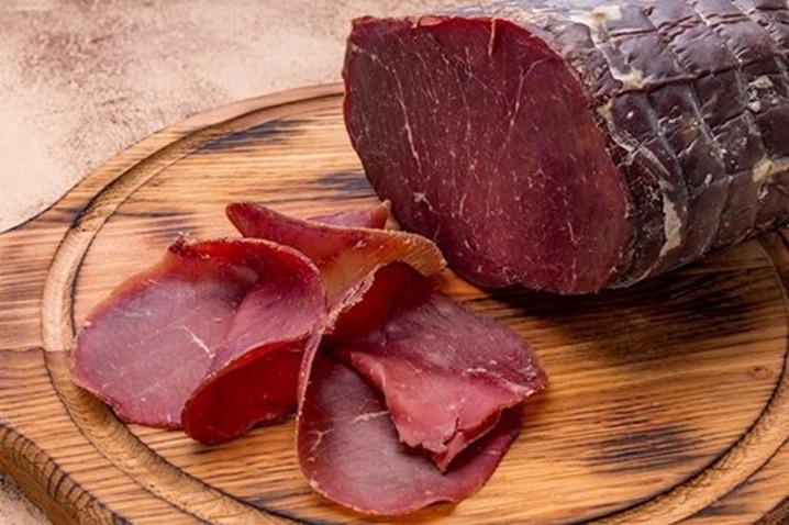Bresaola, dry-cured Italian beef, sliced on a wooden board
